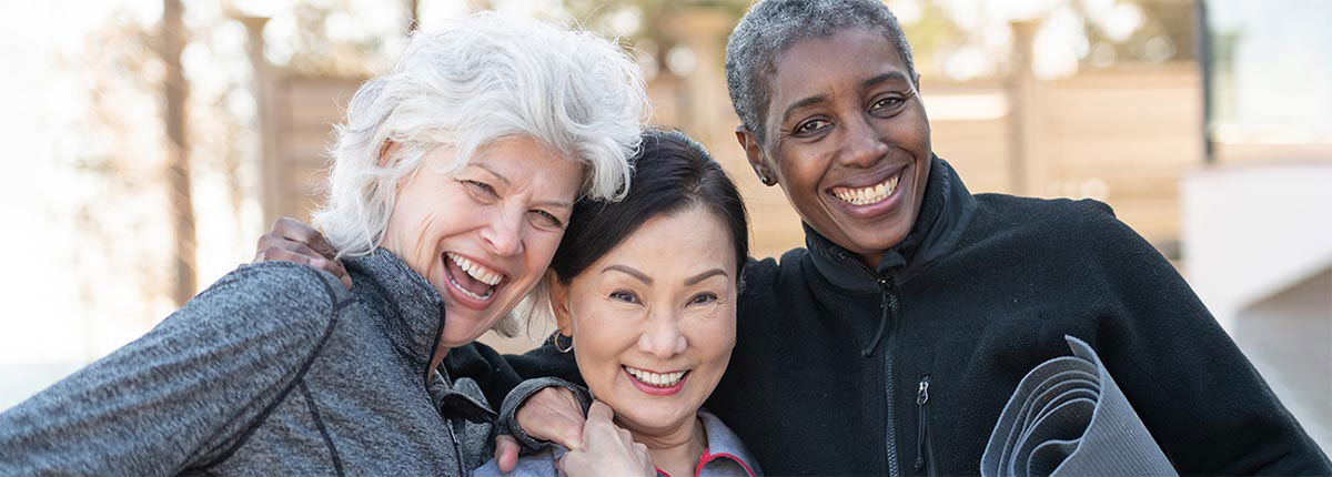 three friends posing heading to a yoga class smiling with their permenent dentures on implants
