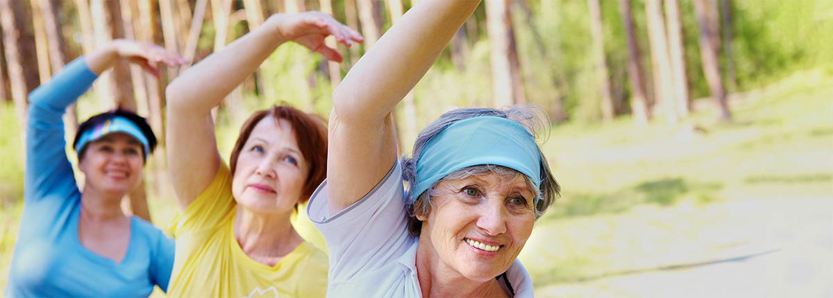 Three friends practicing yoga in a park smiling with their full dentures from Steven T. Feige